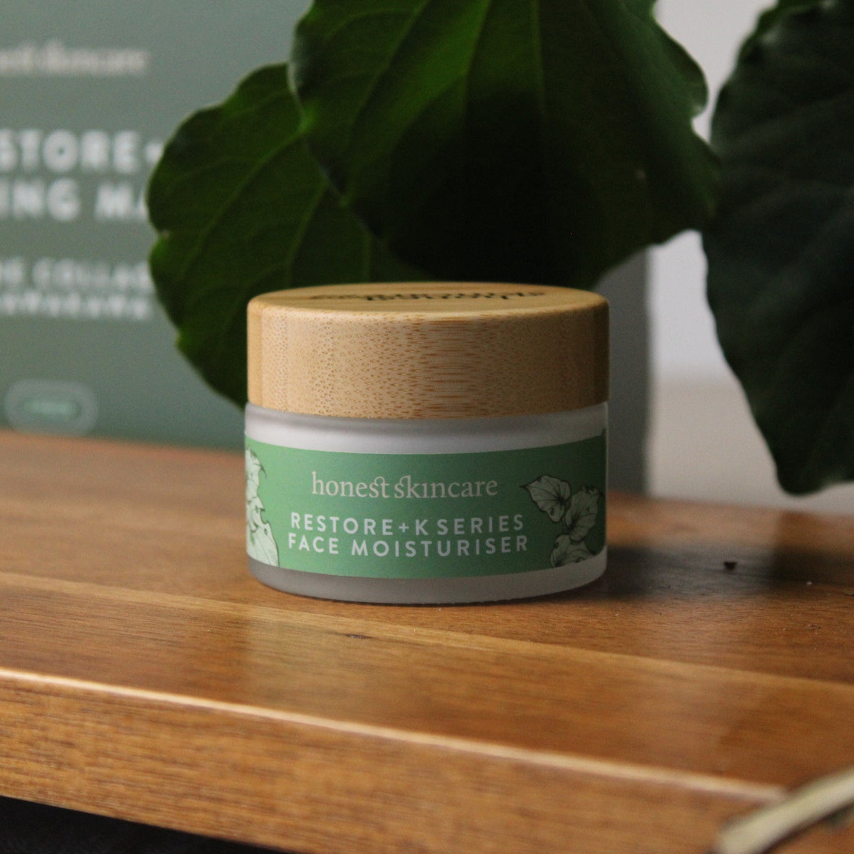 Hydrating facial cream in a bamboo jar on a wooden surface with lush green leaves in the background.