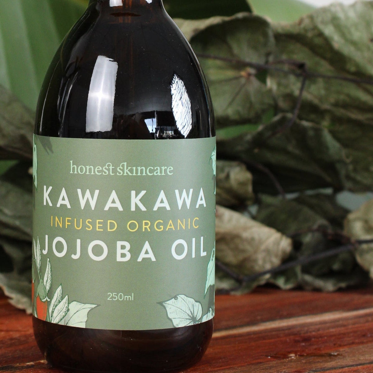 Kawakawa Jojoba Oil for Skin - Organic, 250ml bottle on wooden surface among leaves.