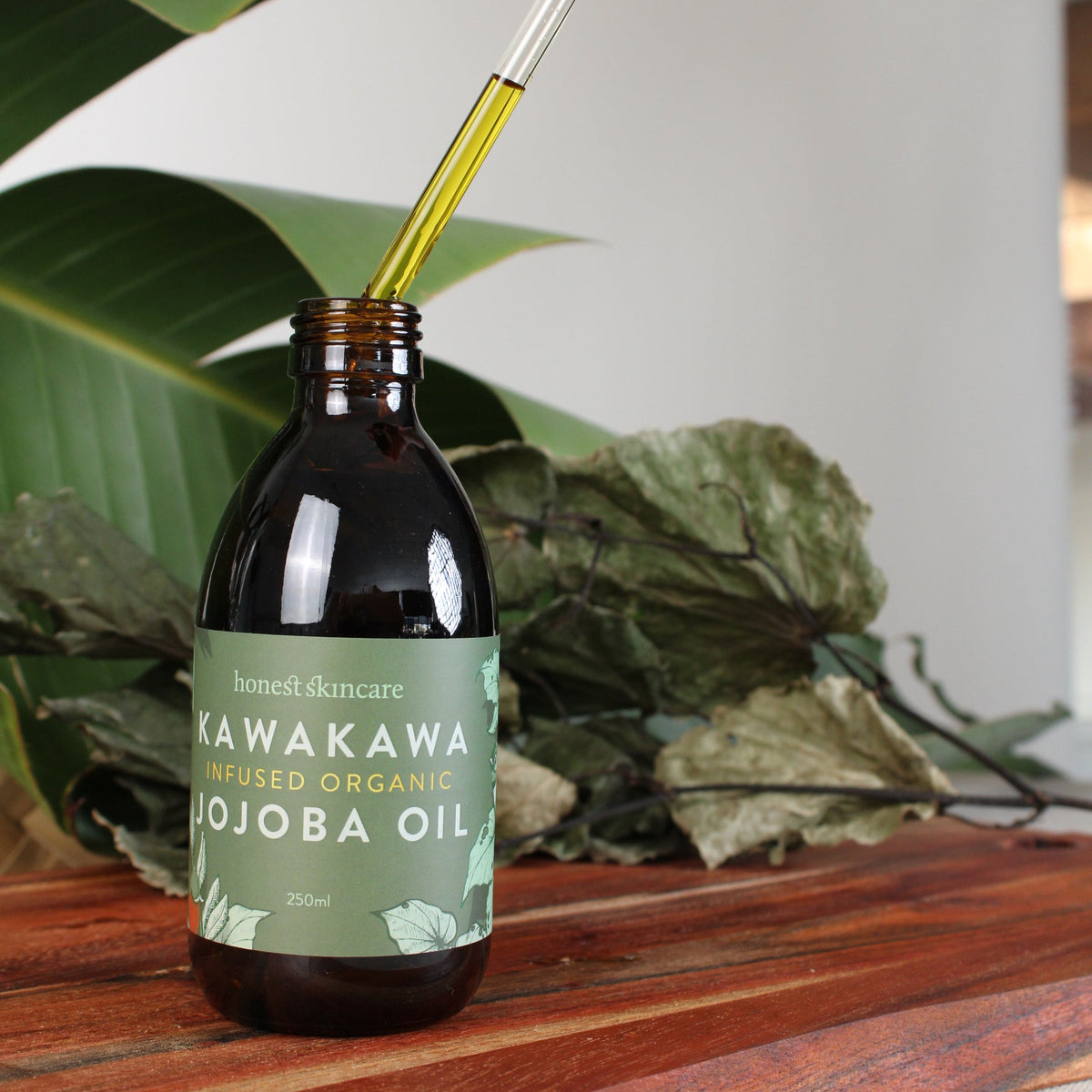 Kawakawa Jojoba Oil for Skin in amber glass bottle with dropper on wooden surface.