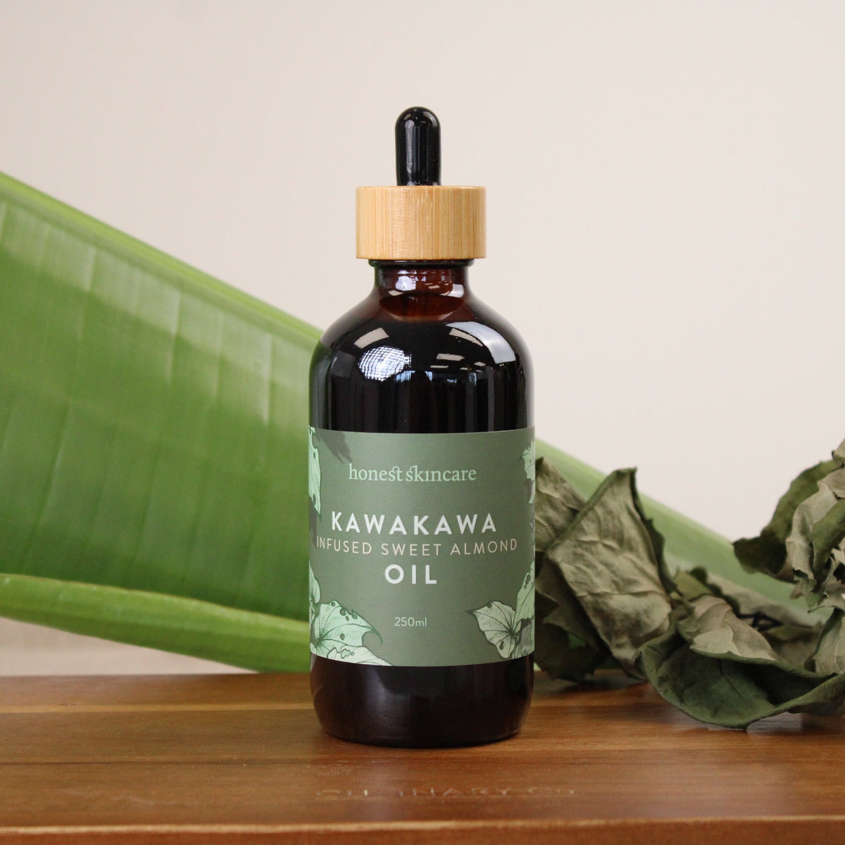 Kawakawa infused sweet almond oil for skin in a glass bottle on a wooden surface.
