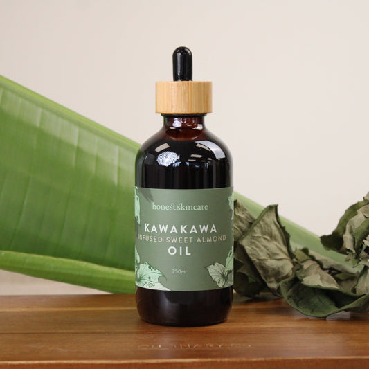 Kawakawa infused sweet almond oil for skin in a glass bottle on a wooden surface.