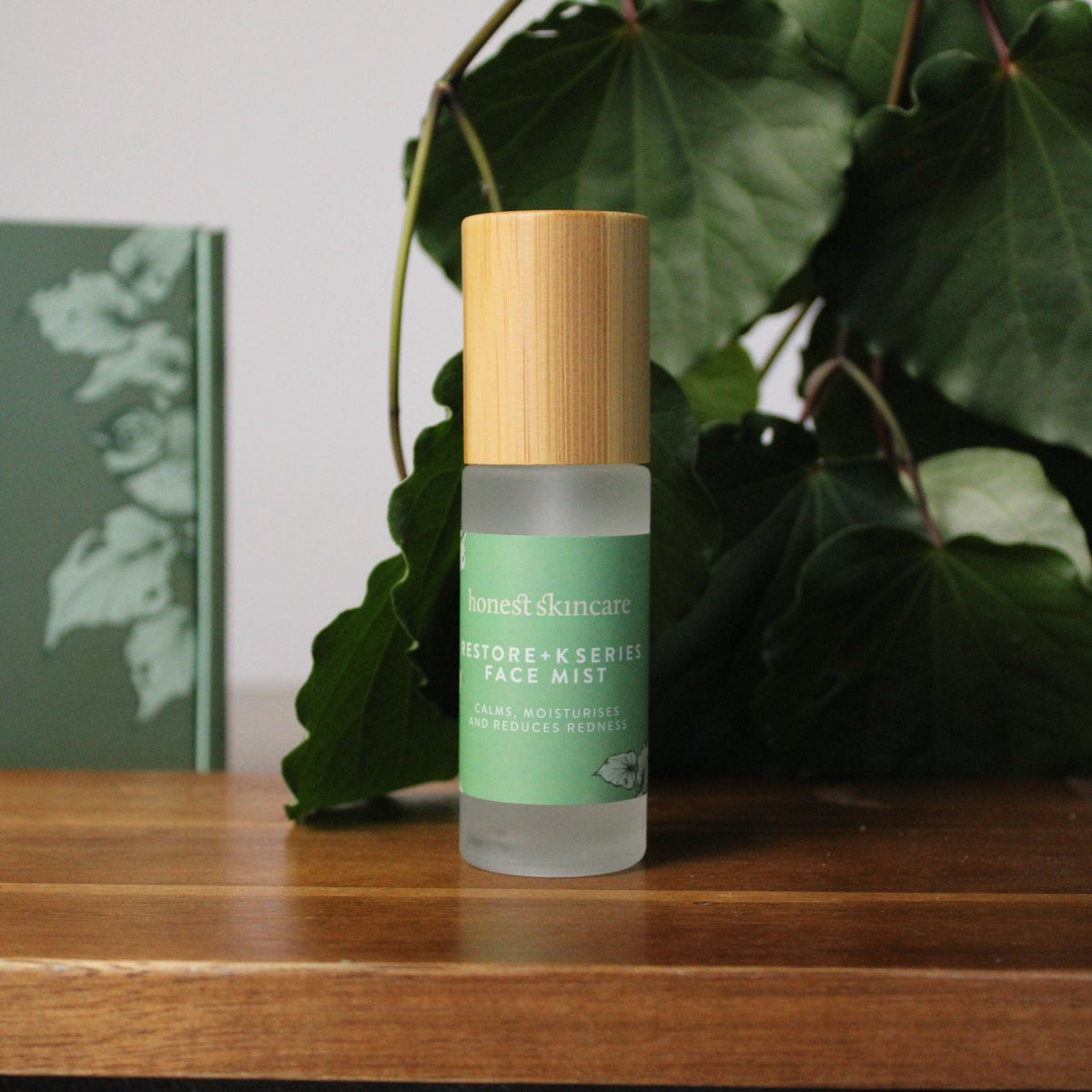 Bottle of skincare facial mist with green label on a wooden surface with leaves in the background Marine melting best collagen mask korean skincare