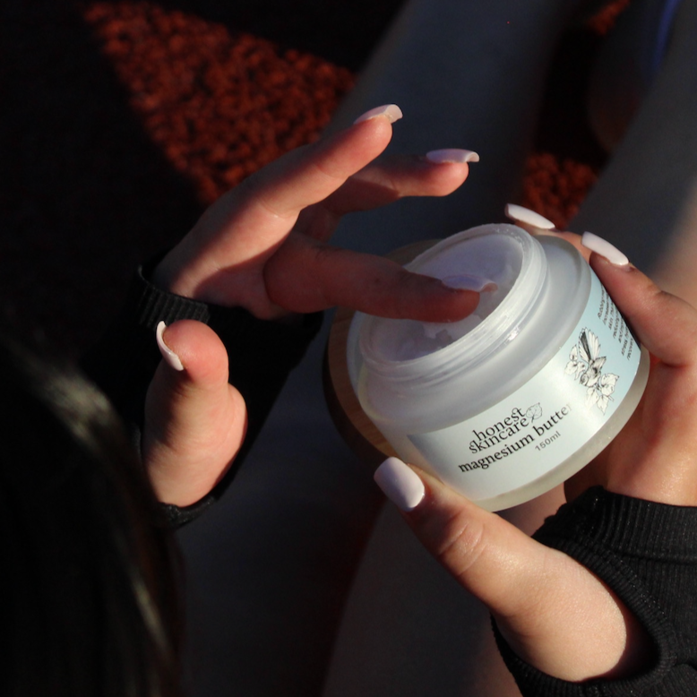 Hands applying magnesium butter from jar, promoting magnesium for muscle recovery and relaxation.