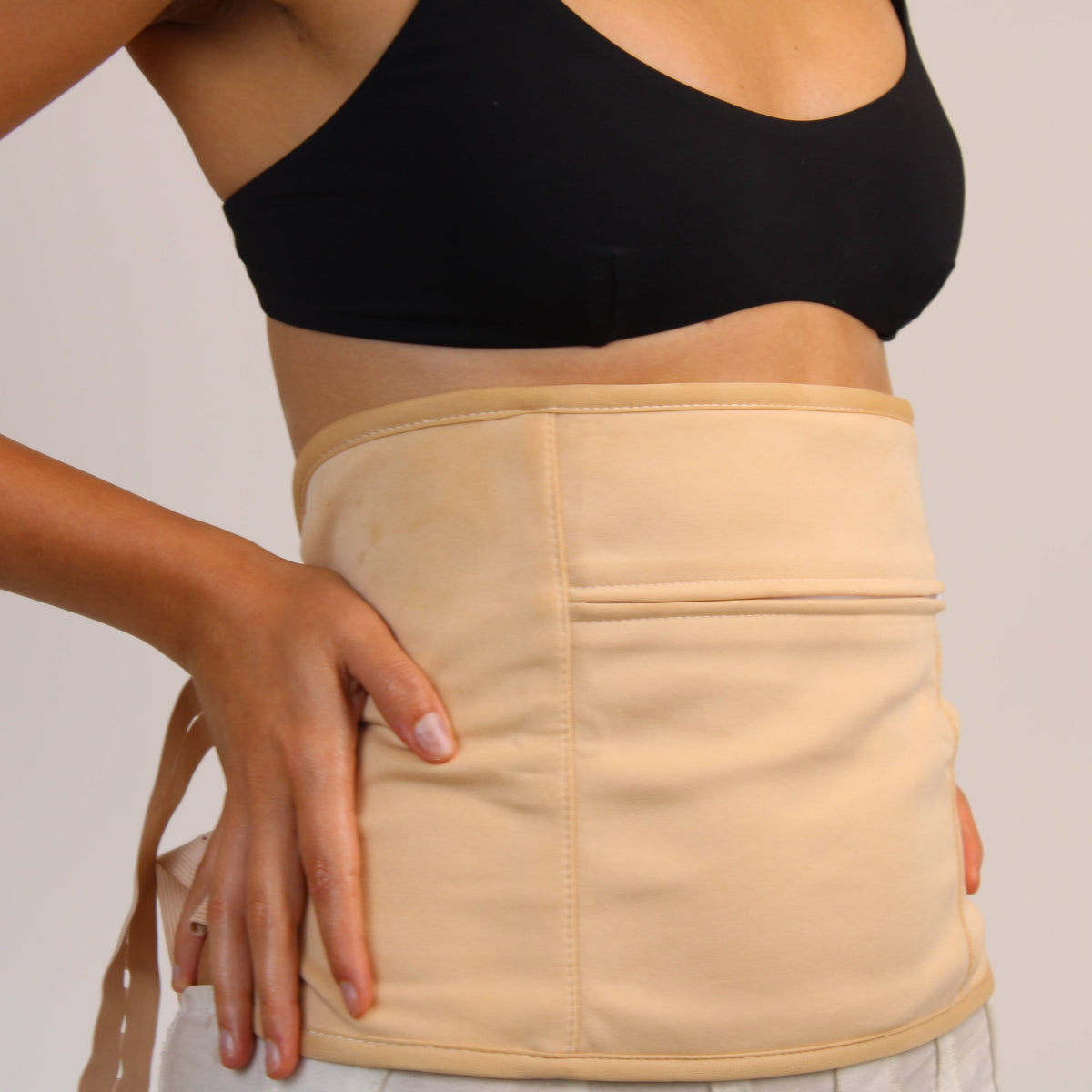 Woman wearing a nude organic castor oil waist trainer for wellness and body shaping.