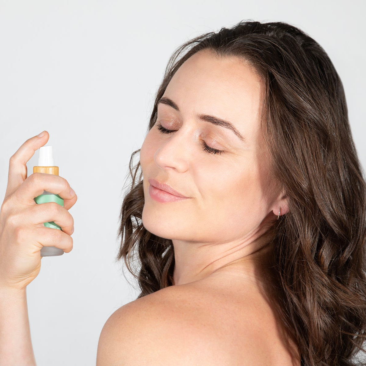 Woman applying the Collagen Melting Mask spray, showcasing healthy glowing skin and natural beauty.