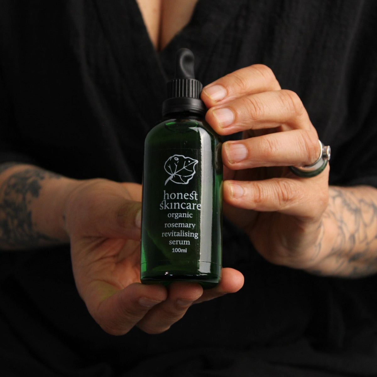 Person holding a bottle of Honest Skincare organic rosemary oil for hair revitalising serum, 100ml.