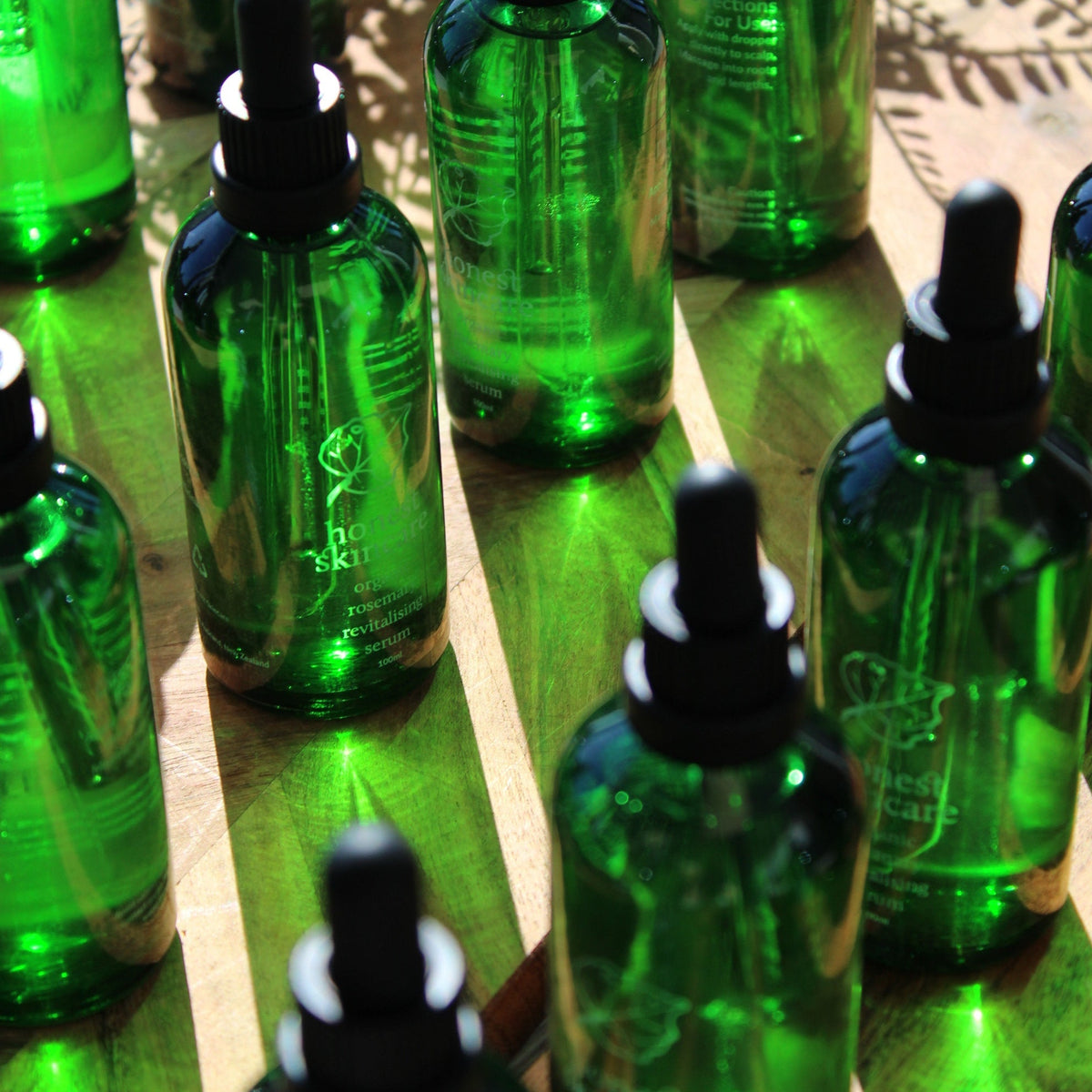 Rosemary oil for hair in green glass bottles on a wooden surface, highlighting organic hair serum.