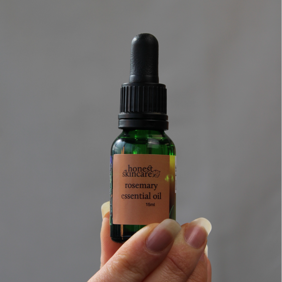 Hand holding a bottle of rosemary essential oil benefits for both skin and hair