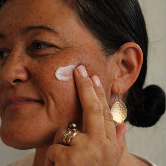 Woman applying Kawakawa Ultra-Nourishing Moisturiser for all skin types on her cheek.