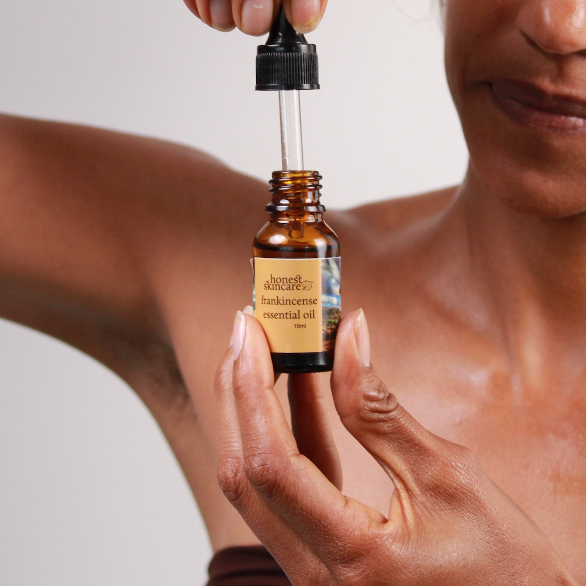 Person holding a dropper bottle of frankincense essential oil benefits for mental and physical wellbeing.
