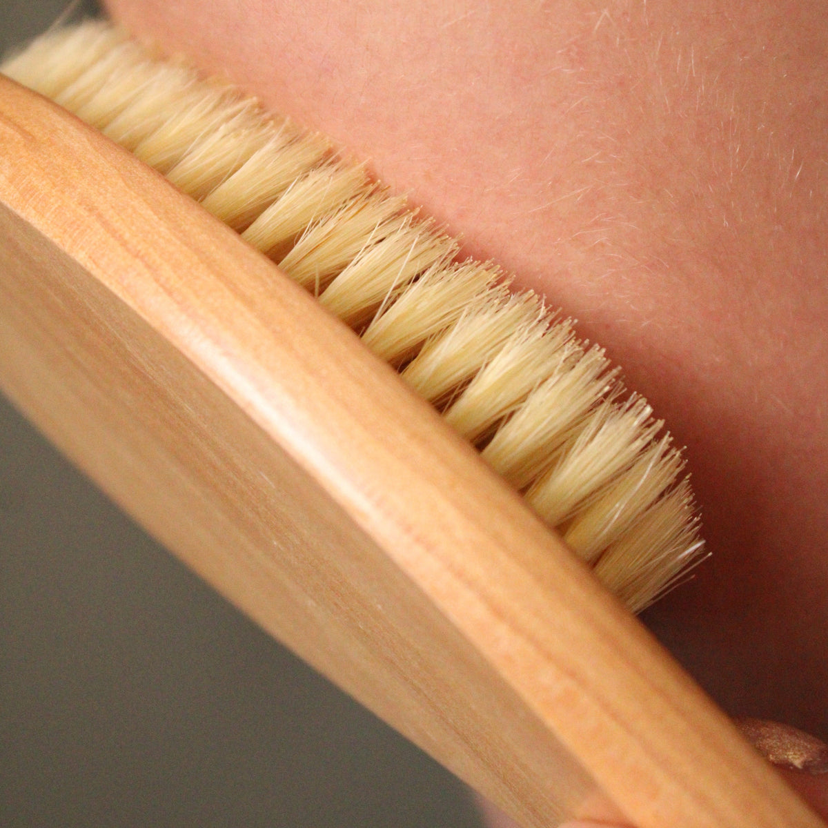 Castor Oil Detox Kit natural bristle dry brush being used on a person's skin