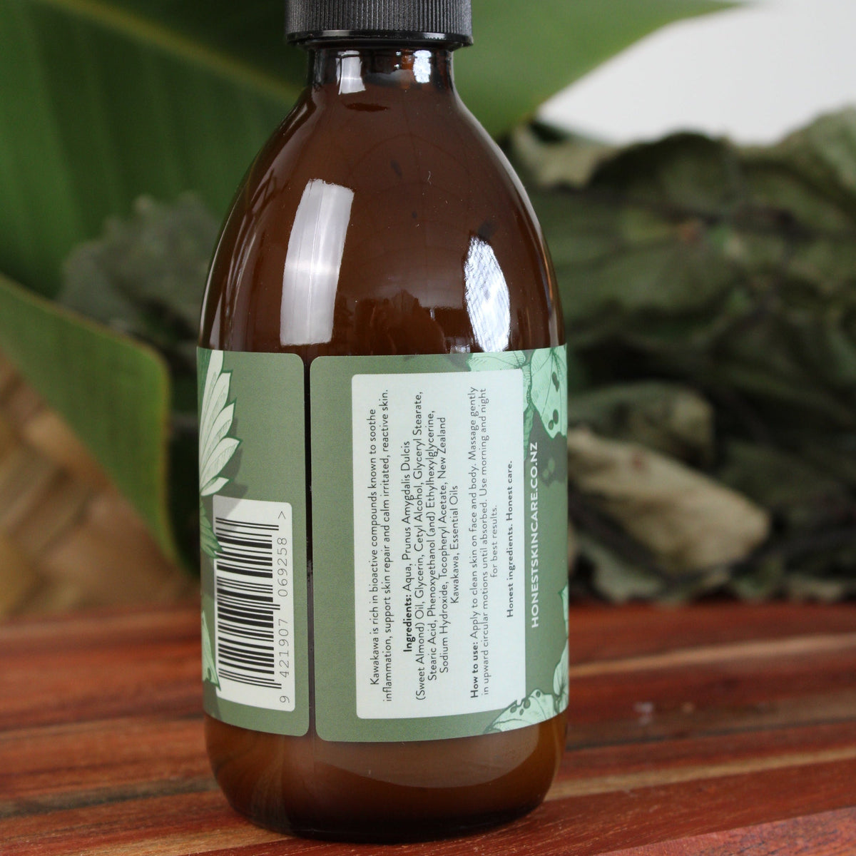 kawakawa moisturiser 250ml with green label and black pump on a wooden surface with leaves in the background
