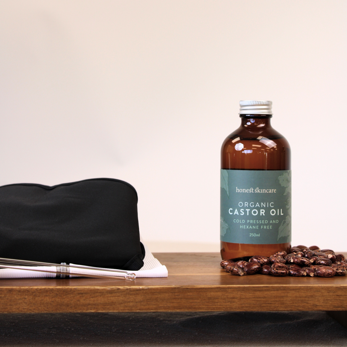 Bottle of organic castor oil on a wooden surface with shoulder wrap which comes in the castor oil shoulder pack