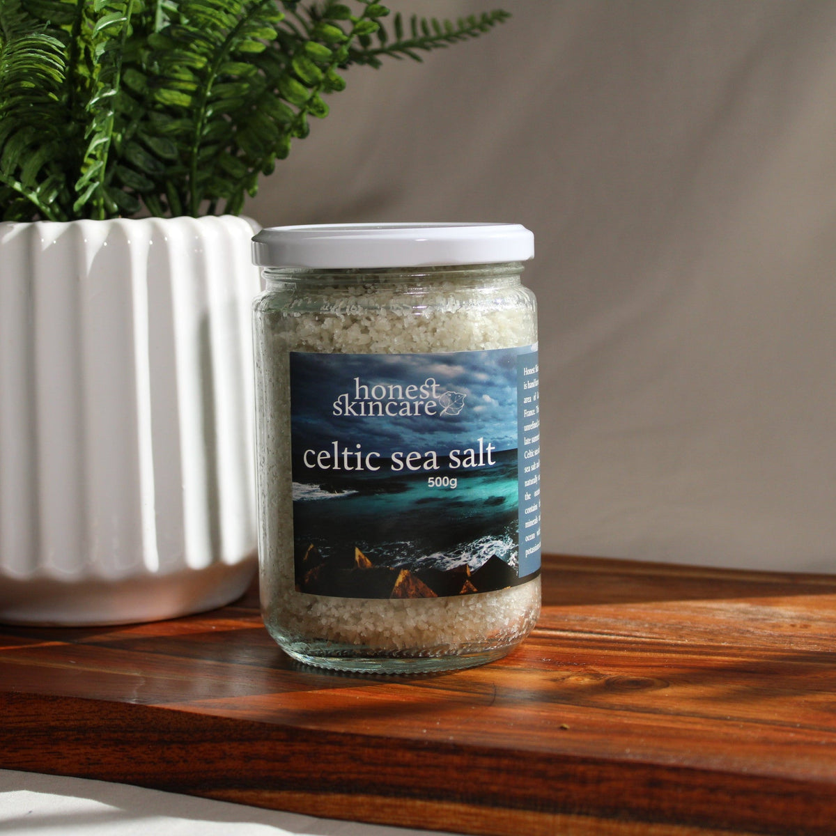 Jar of Celtic sea salt with a plant on a wooden surface