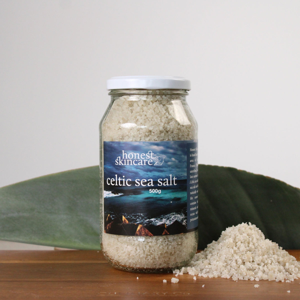 Jar of 'honest & sincere' Celtic sea salt on a wooden surface with a leaf in the background