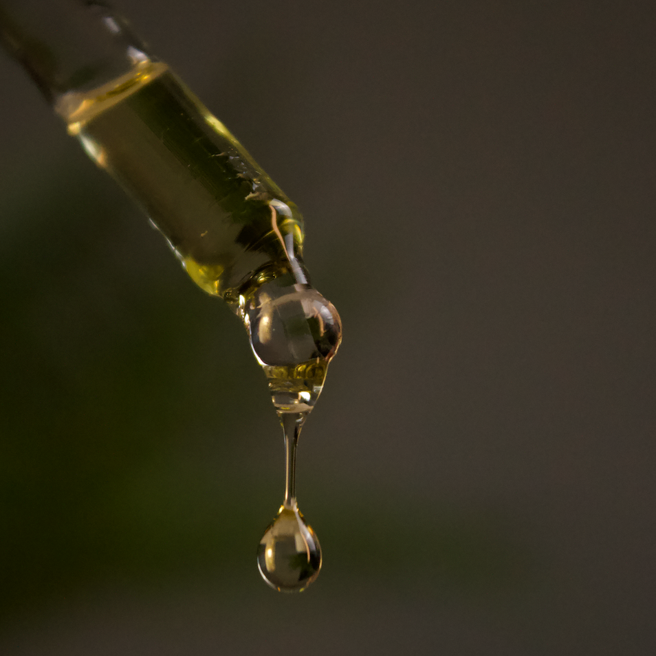 Jojoba oil for skin dropping from a pipette, showcasing its organic texture and moisture benefits.
