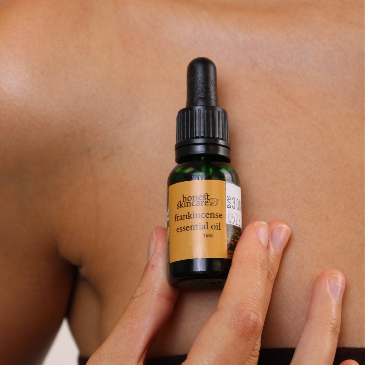 Person applying frankincense essential oil on their back, highlighting frankincense essential oil benefits.
