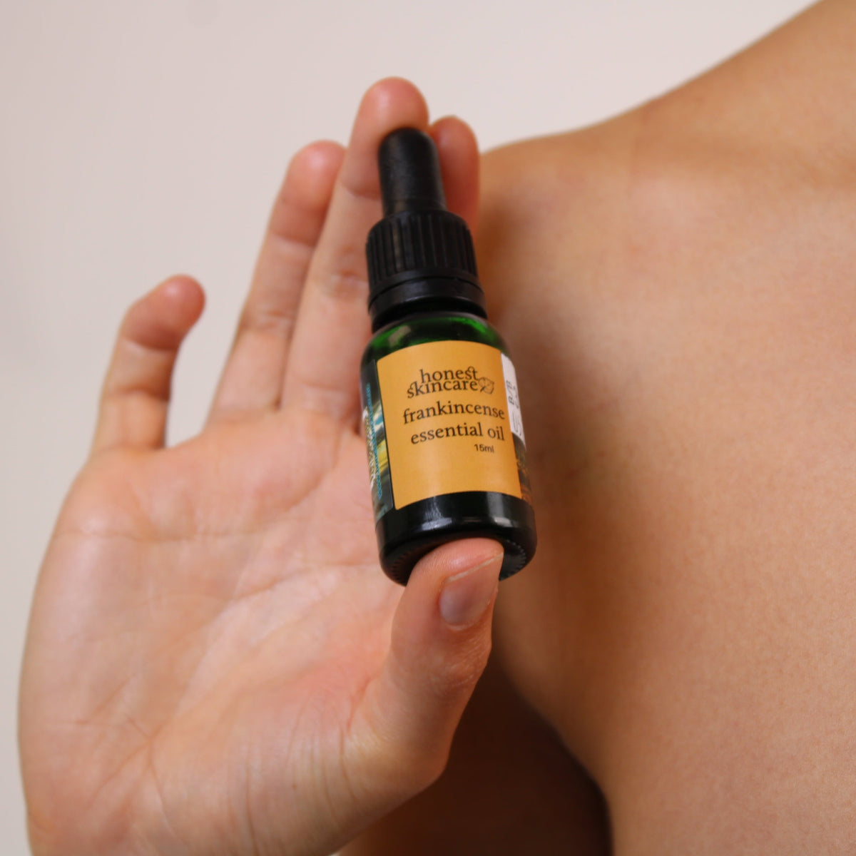 Castor Oil Detox Kit - person holding frankincense essential oil bottle, featured in Honest Skincare's wellness ritual.