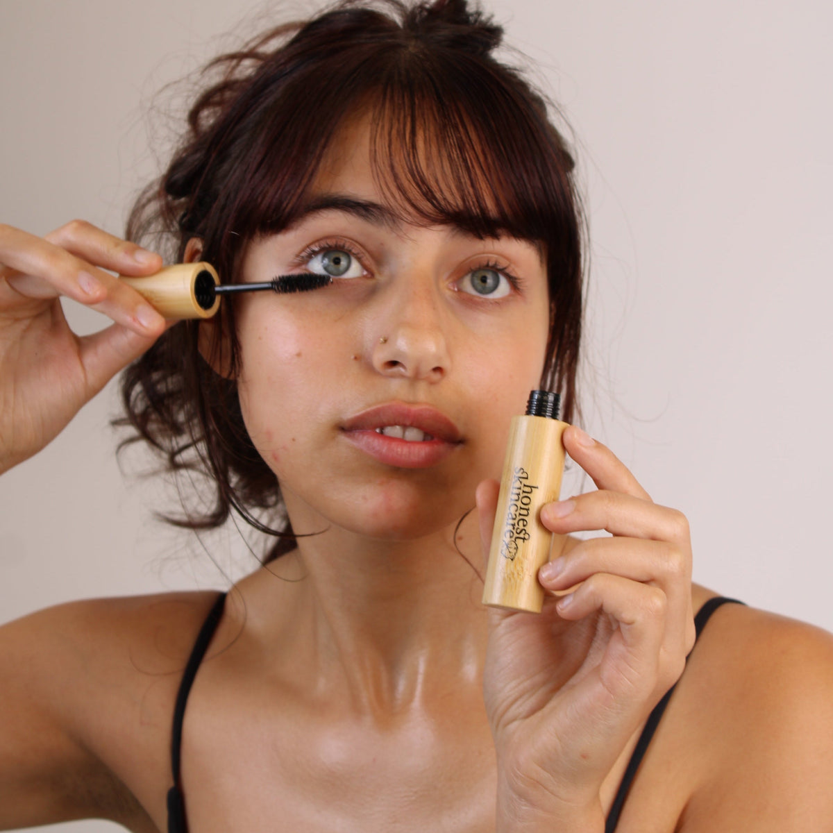 A young woman applying castor oil for eyelashes with a lash brush for hair growth oils for fuller, healthier-looking lashes.