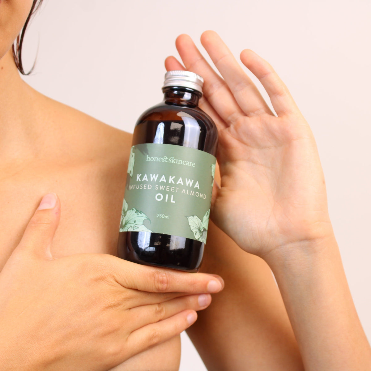 Sweet almond oil for skin - Kawakawa infused bottle held by a person.