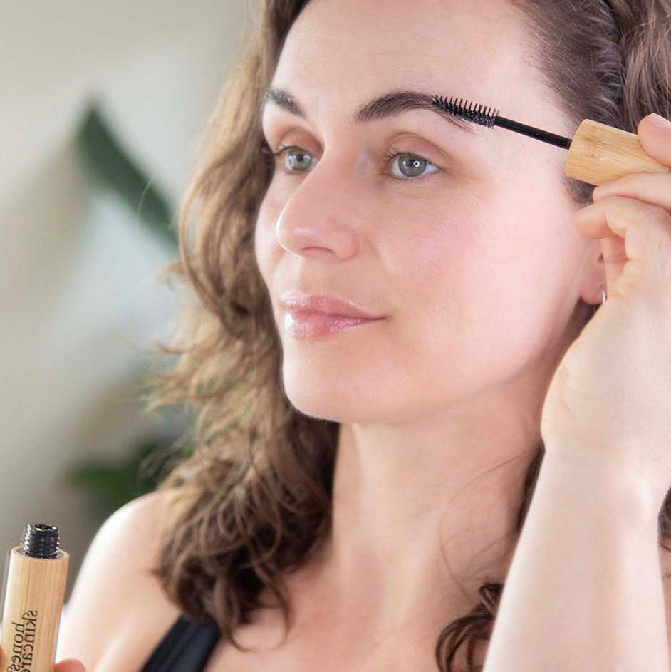 Woman applying castor oil for eyelashes with a lash and brow brush for fuller, healthier lashes.