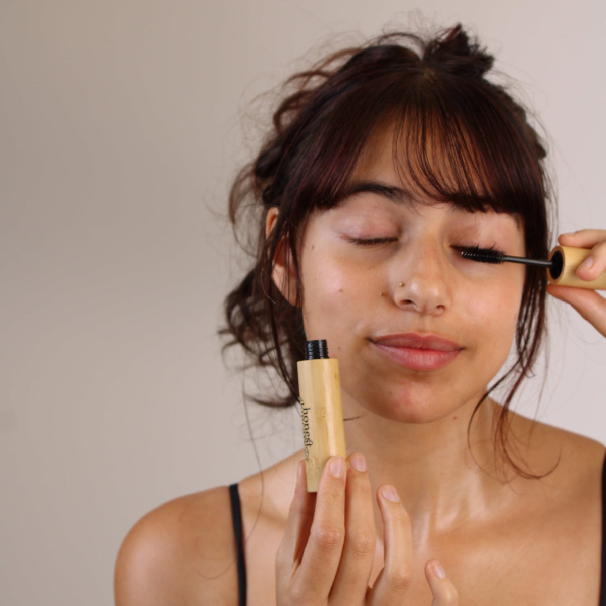 Woman applying castor oil for eyelashes with a mascara brush, showcasing organic lash and brow care.