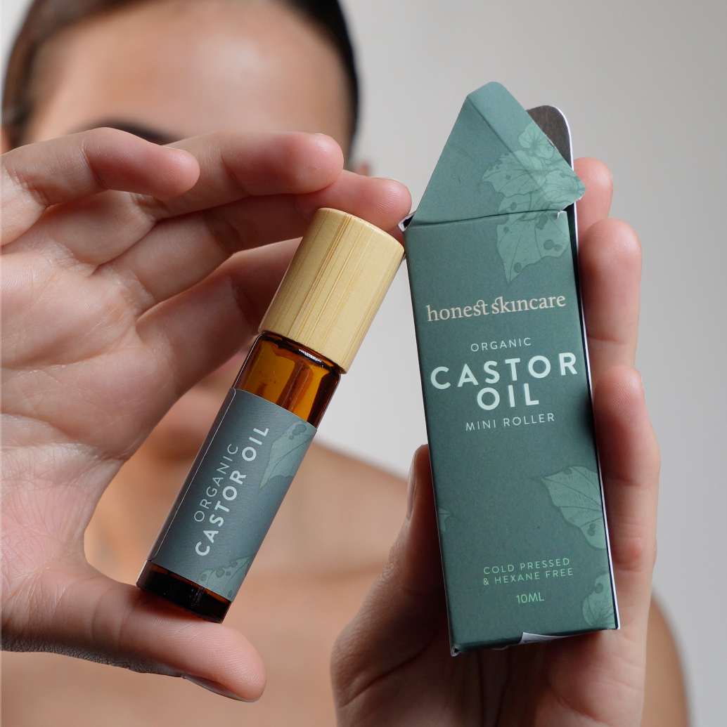 Organic Castor Oil Mini Roller in hand with box, showcasing cold pressed and hexane free product.