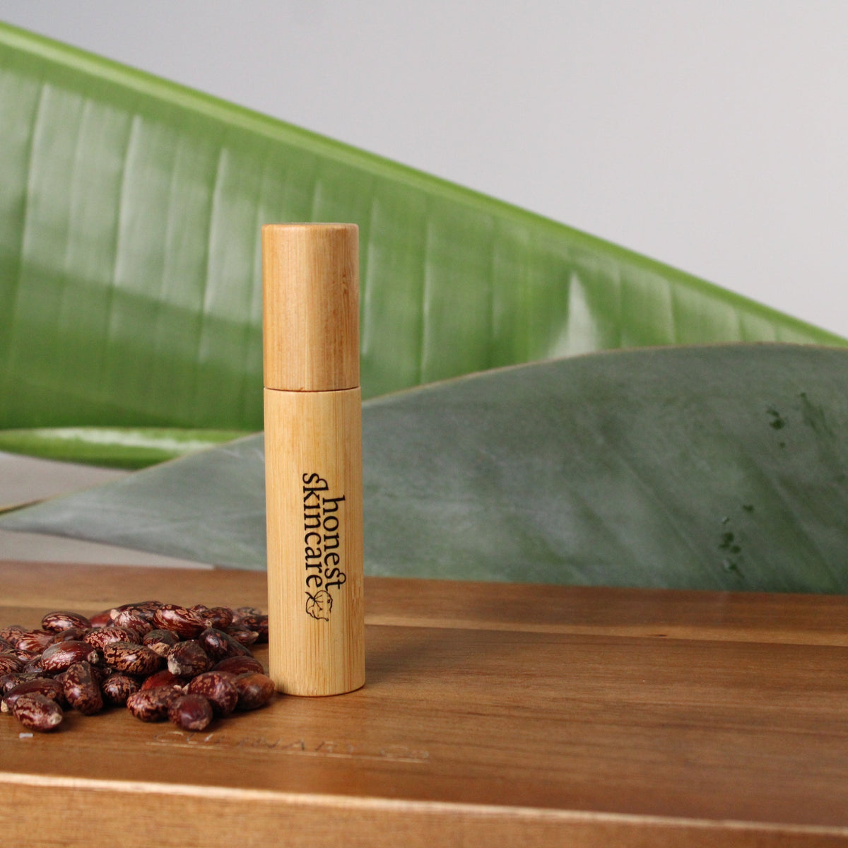 Castor Oil for Eyelashes: Organic Castor Oil Lash & Brow Brush placed on a wooden surface with castor seeds