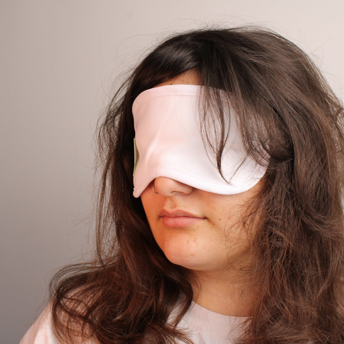 Woman wearing a Castor Oil Eye Treatment Wrap for soothing eye care and relaxation.