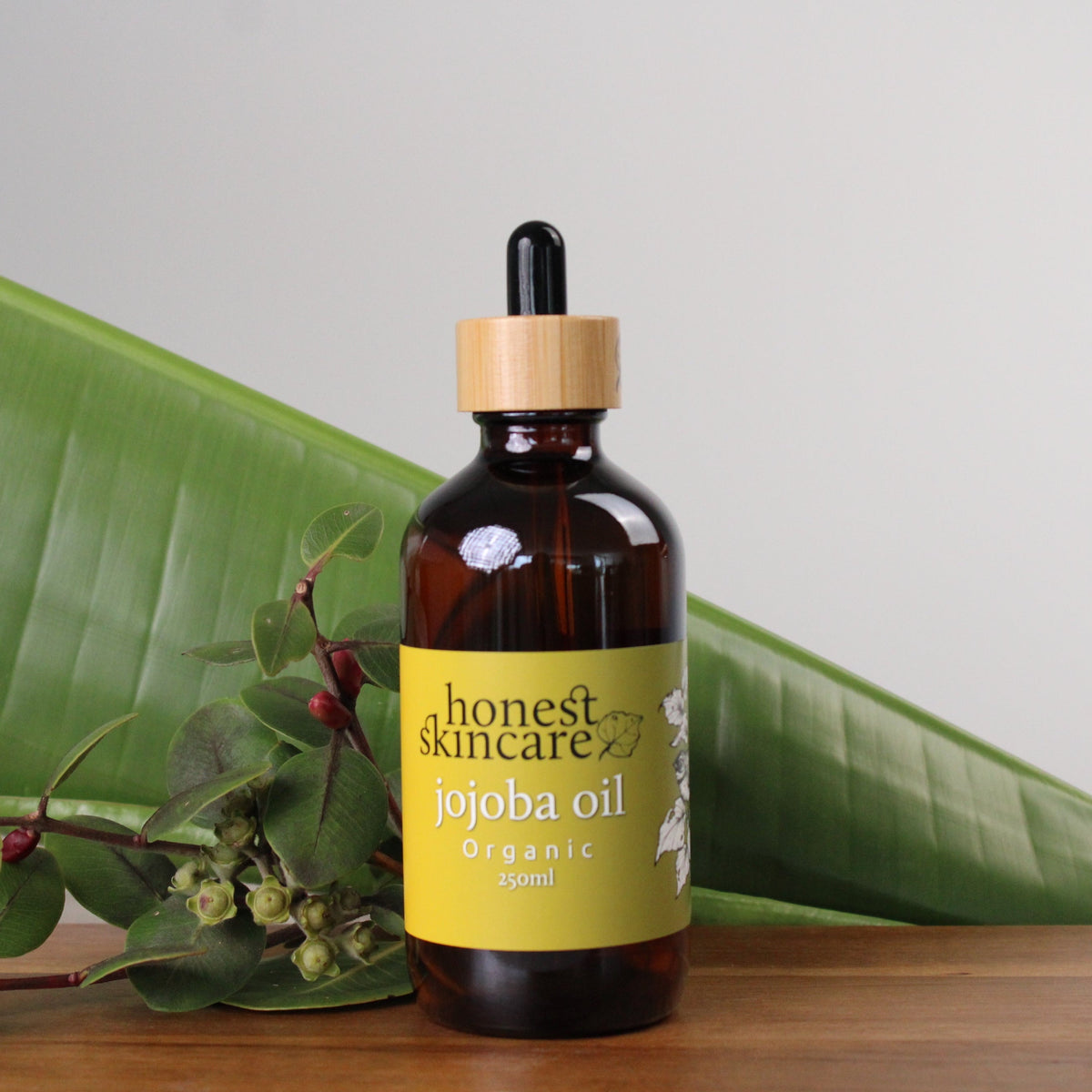 Honest Skincare Jojoba Oil for Skin - Certified Organic 250ml bottle with dropper on a wooden surface.