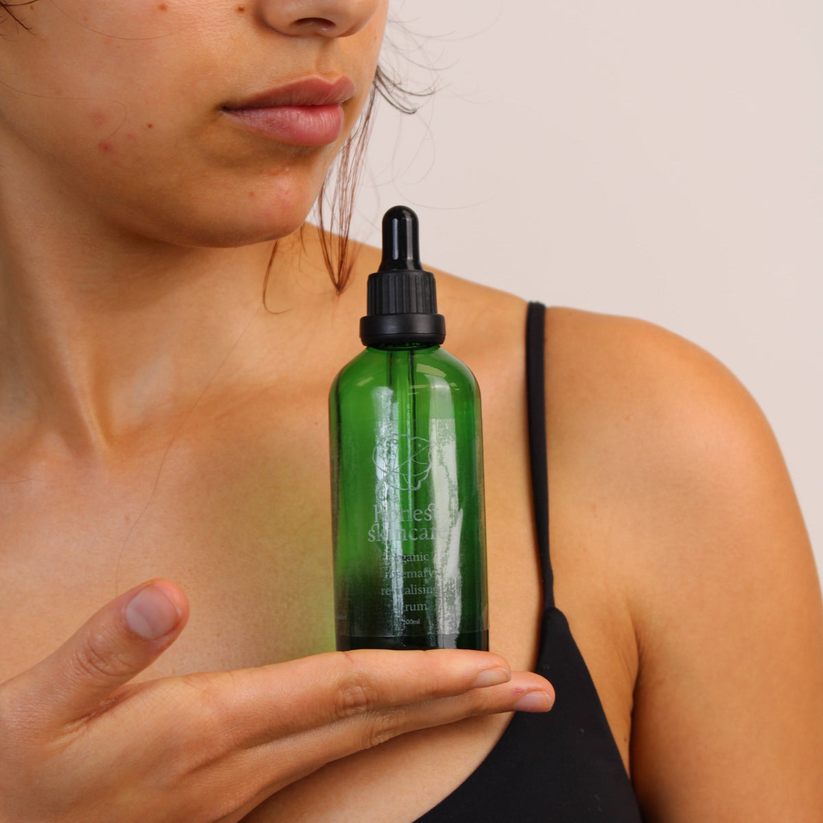Hair growth oils organic castor oil in a green glass dropper bottle held by a model.