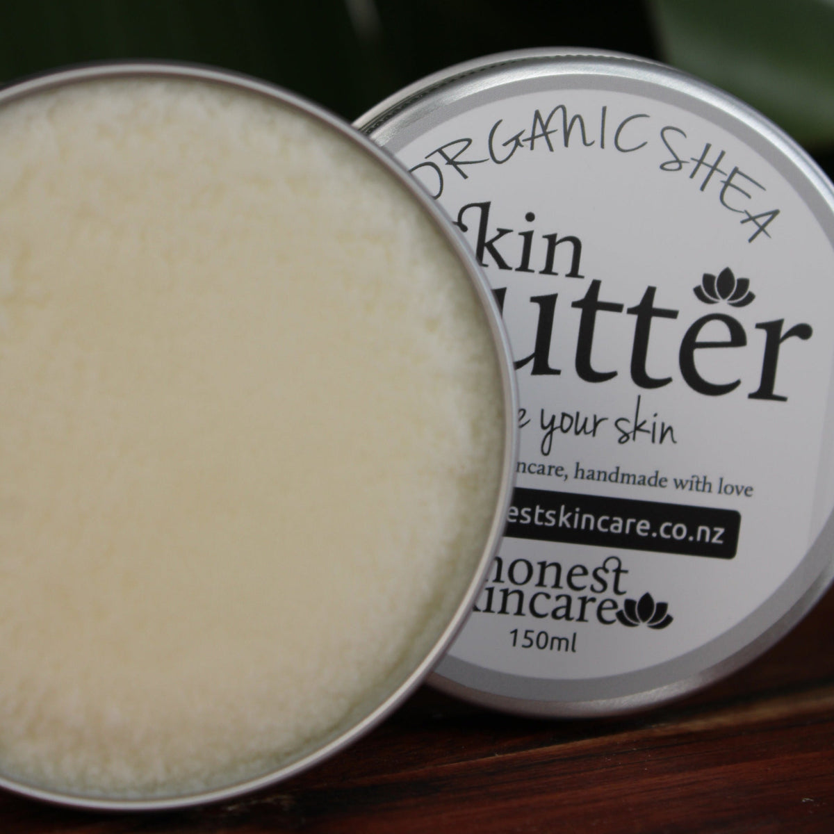 Shea butter body cream in a metallic container, showcasing a smooth, creamy texture, promoting nourishment for skin and hair.