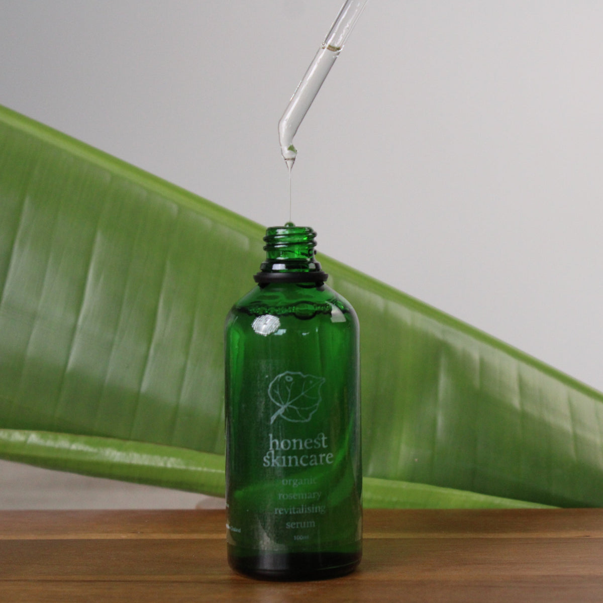 Rosemary oil for hair in a green glass bottle with dropper, promoting natural hair revitalization.